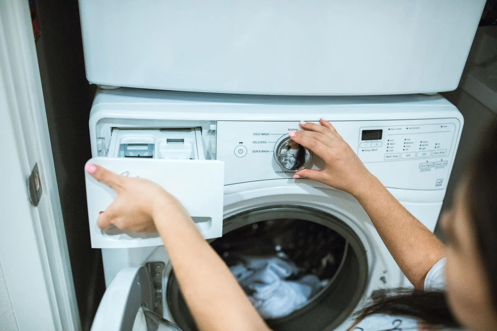 Person using washing machine detergent drawer