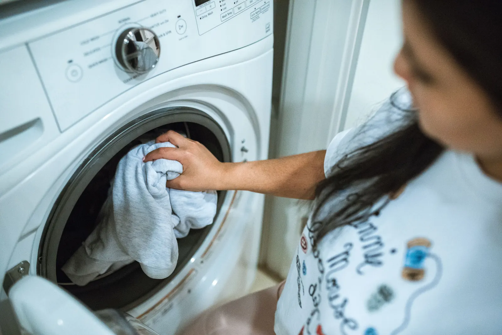 Person loading clothes into a front-load washing machine